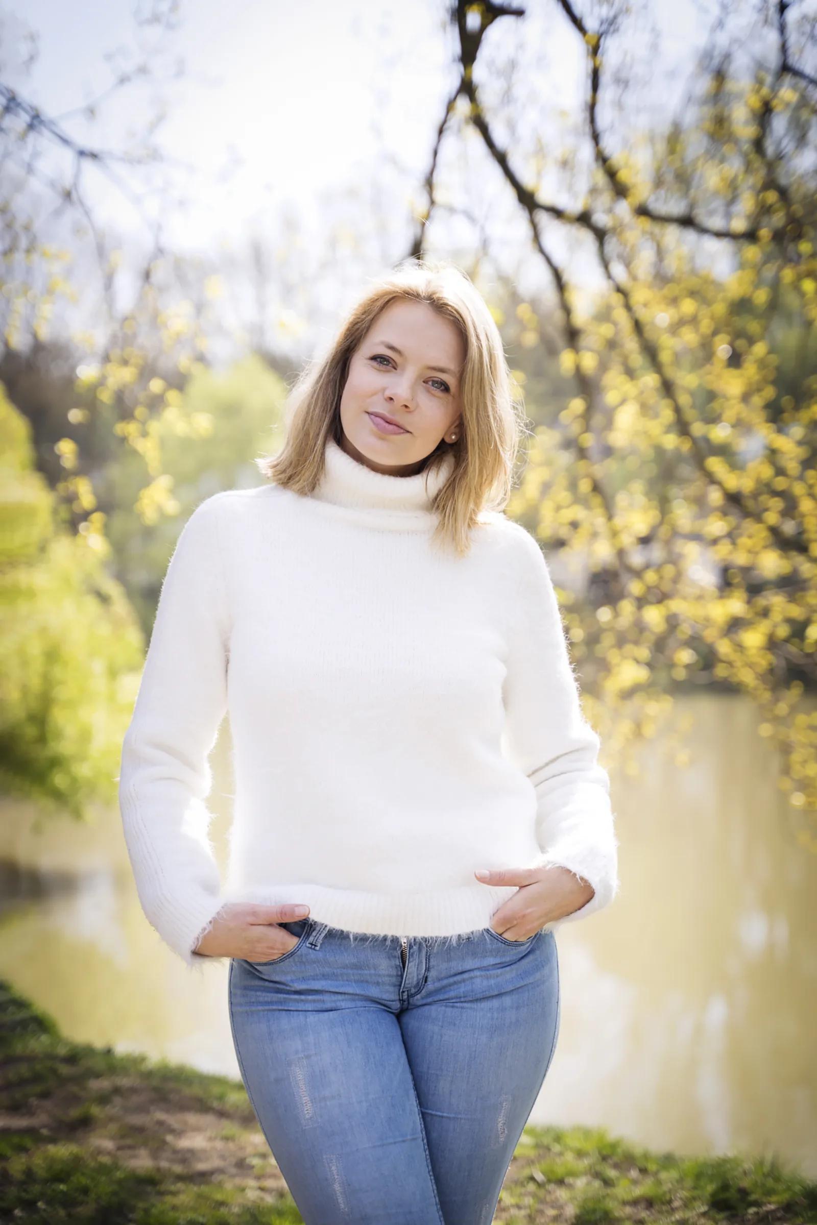 Charline Gervaise, debout au bord d’un étang, au printemps